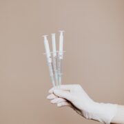 gloved hand holding three vaccines