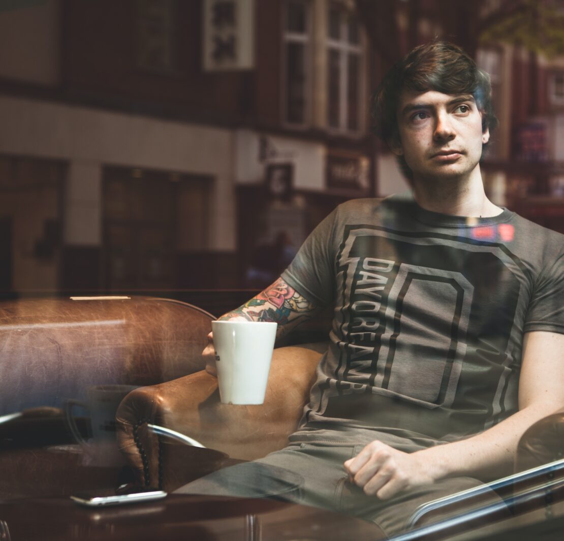 man sitting in cafe staring out window